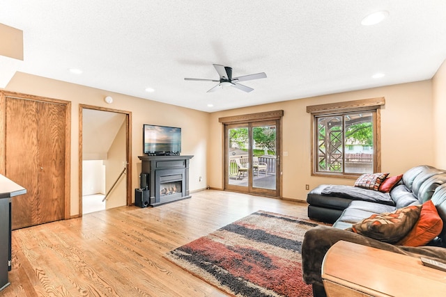 14308 Park Ave, Burnsville, MN 55337 - living area featuring light wood-type flooring, a warm lit fireplace, ceiling fan, recessed lighting, and a textured ceiling