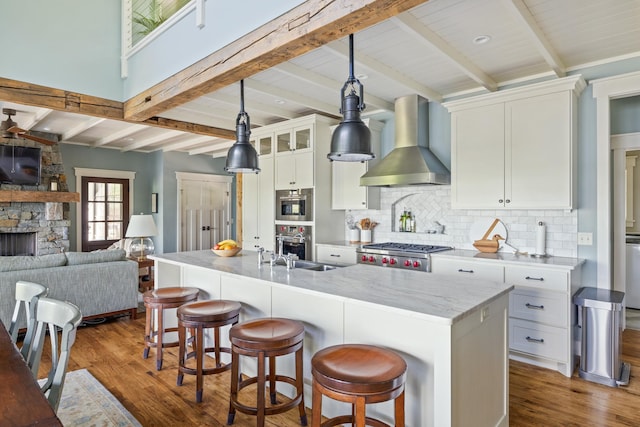 6024 Ojibwa Rd, Brainerd, MN 56401 - kitchen with wall chimney exhaust hood, a stone fireplace, backsplash, wood finished floors, and white cabinets