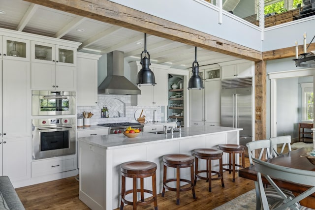 6024 Ojibwa Rd, Brainerd, MN 56401 - kitchen with wall chimney range hood, appliances with stainless steel finishes, dark wood-style floors, beamed ceiling, and tasteful backsplash