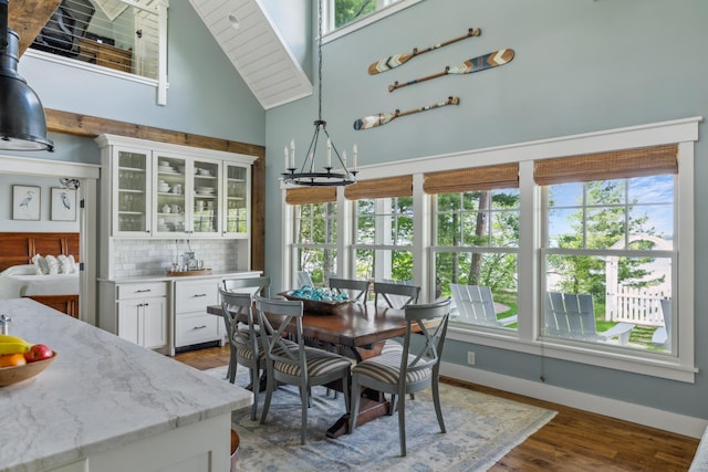 6024 Ojibwa Rd, Brainerd, MN 56401 - dining space with healthy amount of natural light, a high ceiling, a chandelier, wood finished floors, and baseboards