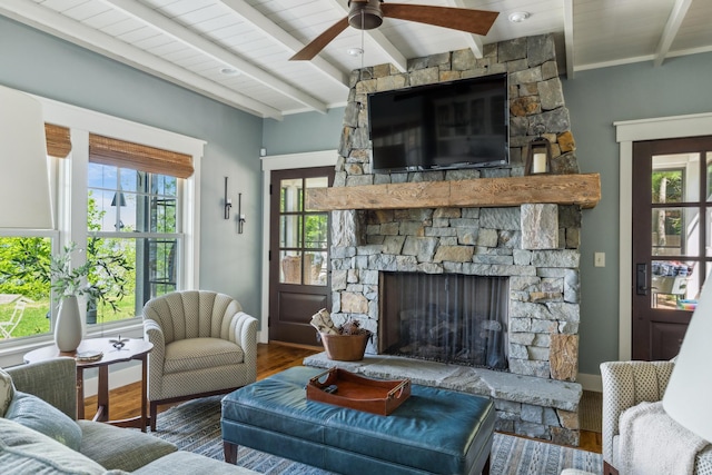 6024 Ojibwa Rd, Brainerd, MN 56401 - living area with beam ceiling, healthy amount of natural light, a stone fireplace, a ceiling fan, and wood finished floors