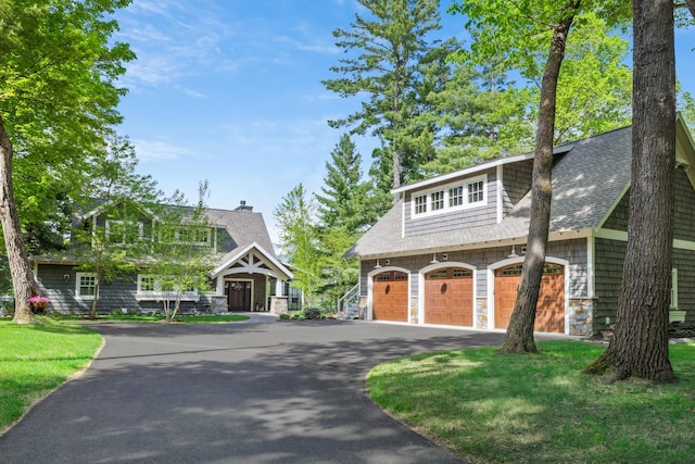 6024 Ojibwa Rd, Brainerd, MN 56401 - view of front facade featuring roof with shingles, stone siding, driveway, a front lawn, and a detached garage