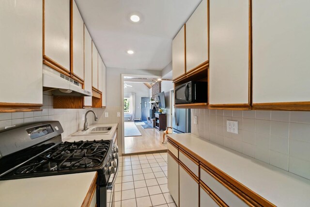 1460 36th St, Minneapolis, MN 55408 - kitchen featuring gas range, under cabinet range hood, a sink, black microwave, and light countertops