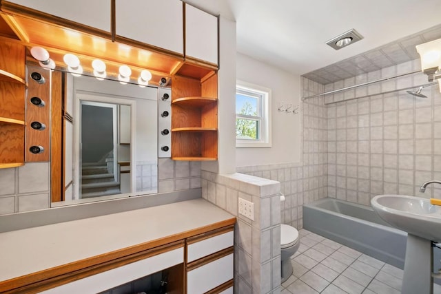 1460 36th St, Minneapolis, MN 55408 - bathroom featuring tile walls, tile patterned floors, toilet, and washtub / shower combination