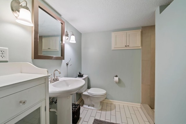 1460 36th St, Minneapolis, MN 55408 - bathroom with toilet, baseboards, a textured ceiling, tiled shower, and a sink
