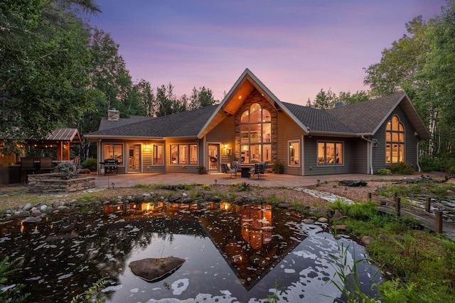 40335 Government Rd, Barry Twp, MN 55037 - back of house at dusk featuring a patio, a garden pond, a fire pit, and a chimney
