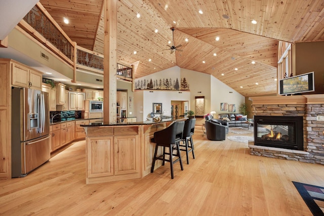 40335 Government Rd, Barry Twp, MN 55037 - kitchen featuring appliances with stainless steel finishes, high vaulted ceiling, light brown cabinets, a breakfast bar, and open floor plan