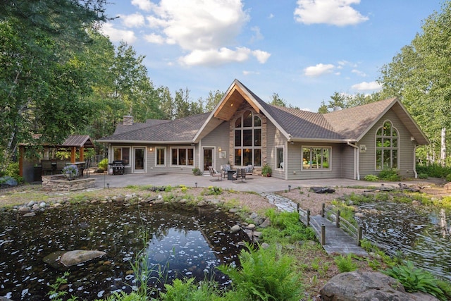 40335 Government Rd, Barry Twp, MN 55037 - rear view of house featuring a small pond, a patio area, a chimney, and roof with shingles