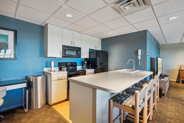 400 Groveland Ave Unit 1512, Minneapolis, MN 55403 - kitchen featuring black appliances, a sink, a breakfast bar area, a paneled ceiling, and light countertops
