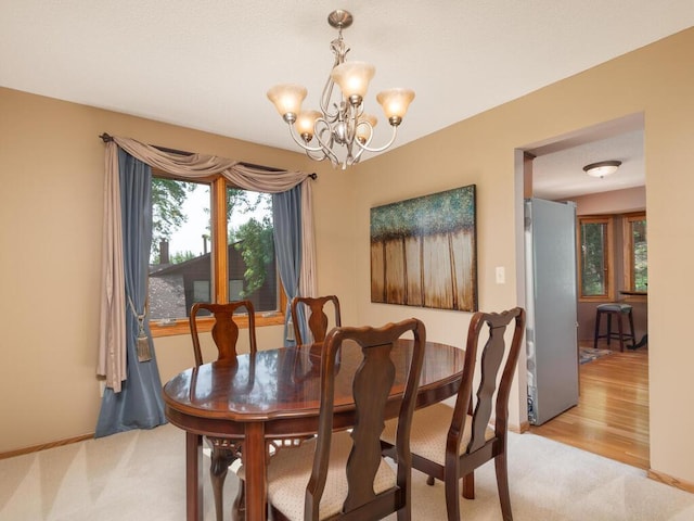 5705 Quinwood Ln N, Plymouth, MN 55442 - dining area with light colored carpet, a chandelier, and baseboards