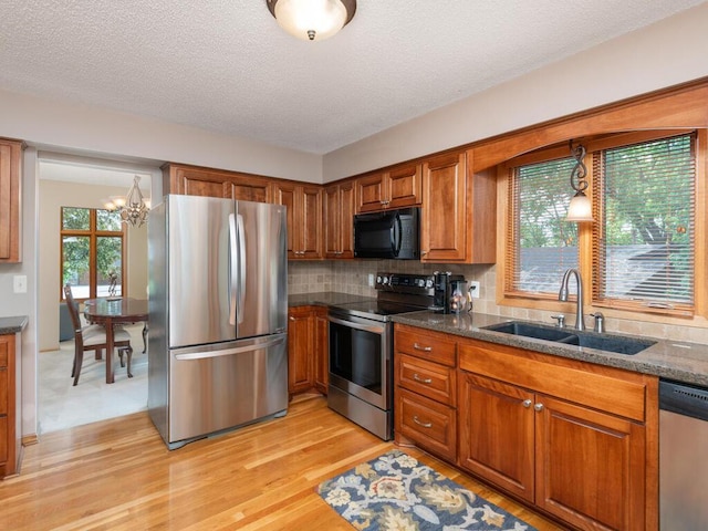 5705 Quinwood Ln N, Plymouth, MN 55442 - kitchen featuring appliances with stainless steel finishes, a sink, brown cabinetry, light wood-style floors, and tasteful backsplash