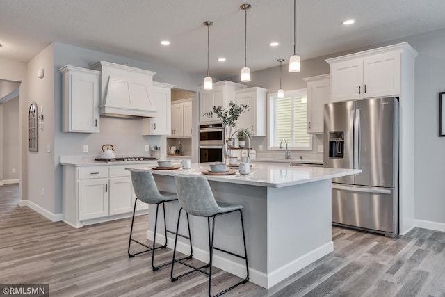 kitchen featuring appliances with stainless steel finishes, light wood-style flooring, white cabinets, a kitchen island, and recessed lighting