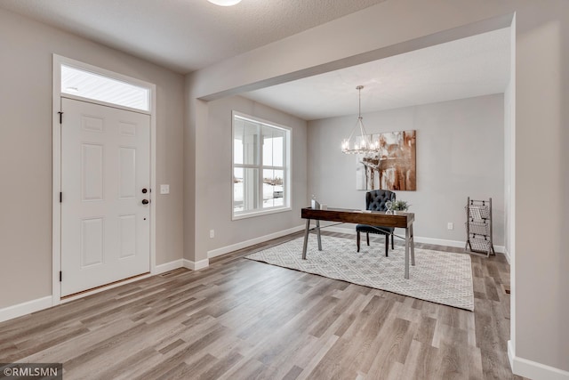 foyer featuring light wood-type flooring, baseboards, and a chandelier