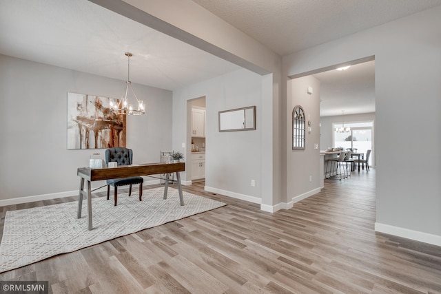 office featuring a chandelier, light wood finished floors, and baseboards