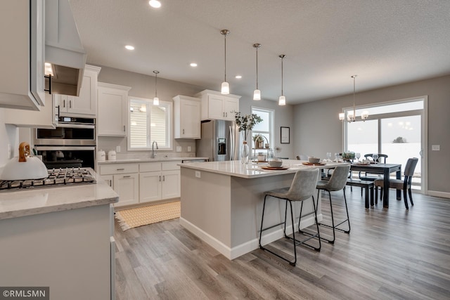 kitchen featuring stainless steel appliances, light wood-style floors, a breakfast bar area, white cabinetry, and recessed lighting