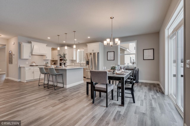 dining area featuring light wood-style flooring, baseboards, a chandelier, and recessed lighting