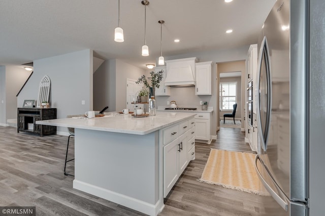 kitchen featuring freestanding refrigerator, custom range hood, white cabinets, light wood-style flooring, and recessed lighting