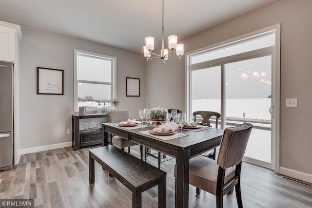 dining room with a chandelier, light wood-style flooring, and baseboards