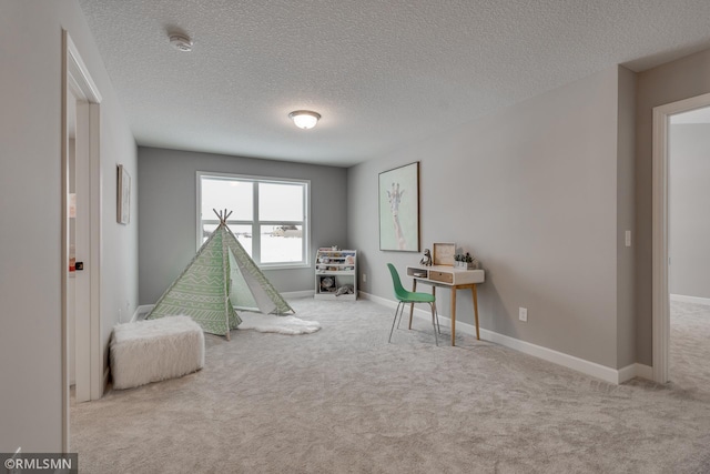 rec room featuring carpet flooring, a textured ceiling, and baseboards