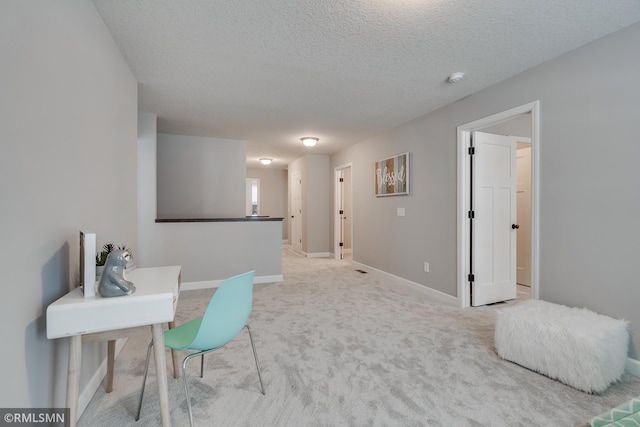 home office with baseboards, a textured ceiling, and light carpet
