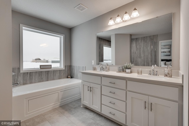 bathroom with double vanity, a bath, and tile patterned floors