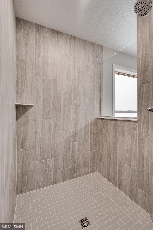 bathroom with a tile shower and a textured ceiling