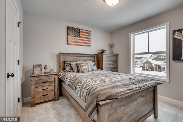 bedroom with light carpet, baseboards, and a textured ceiling