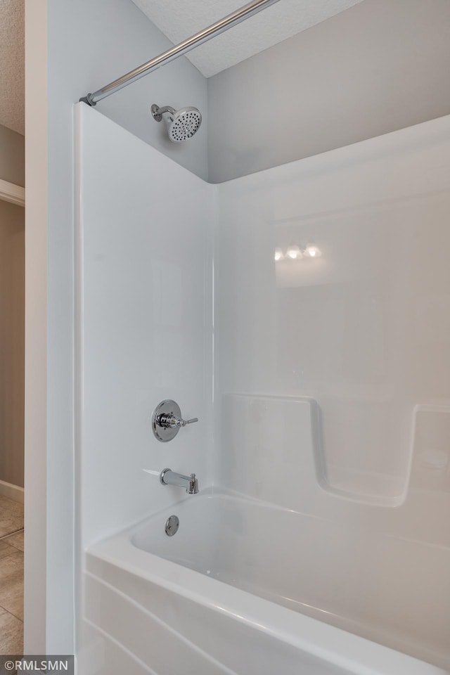 bathroom with tub / shower combination, a textured ceiling, and tile patterned flooring