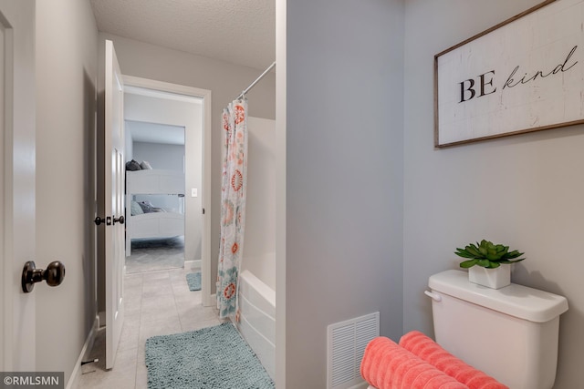 bathroom featuring tile patterned flooring, toilet, baseboards, shower / tub combo with curtain, and a textured ceiling