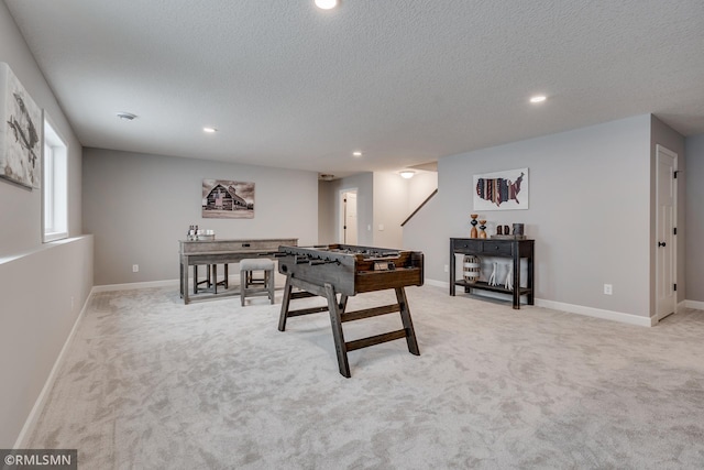 recreation room with recessed lighting, a textured ceiling, light colored carpet, and baseboards