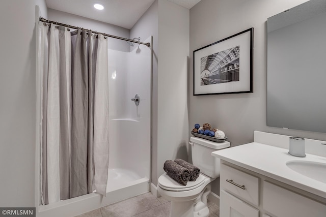 bathroom with a stall shower, toilet, vanity, tile patterned floors, and baseboards