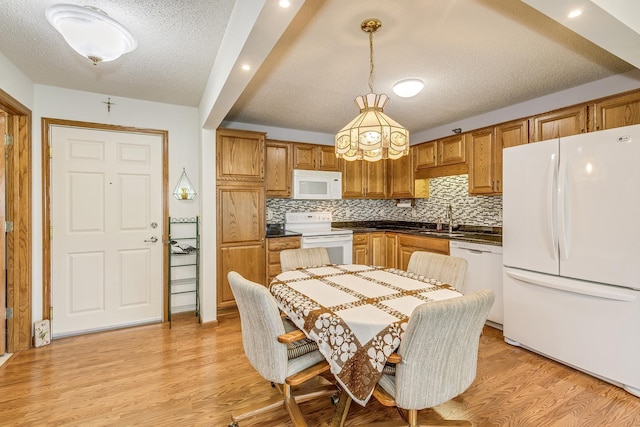 kitchen featuring white appliances, a sink, tasteful backsplash, dark countertops, and a textured ceiling