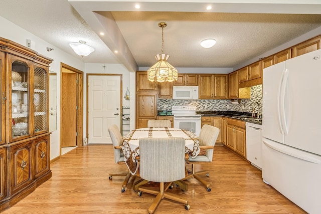 kitchen with white appliances, light wood-style flooring, decorative backsplash, a sink, and a textured ceiling