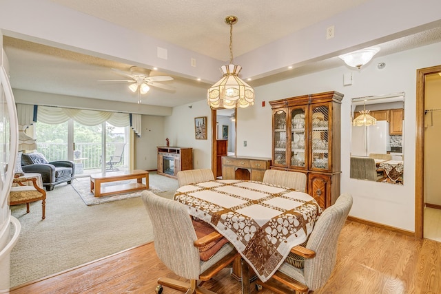 dining space featuring light wood-type flooring, a ceiling fan, and a textured ceiling
