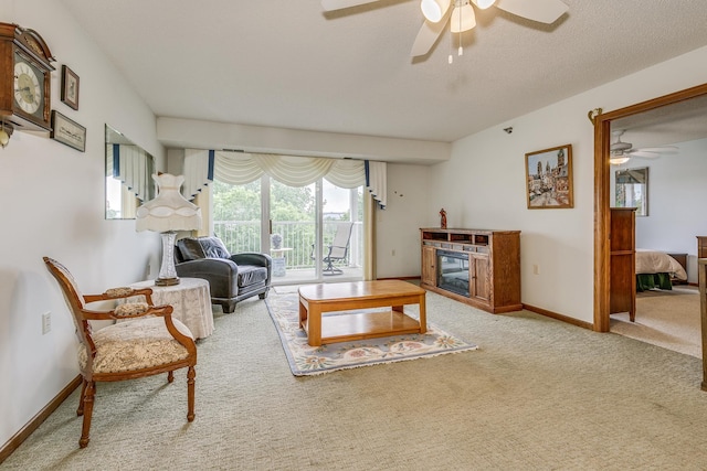 living area with a ceiling fan, carpet flooring, baseboards, and a glass covered fireplace