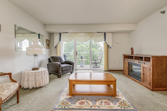living room with light carpet, a glass covered fireplace, and baseboards