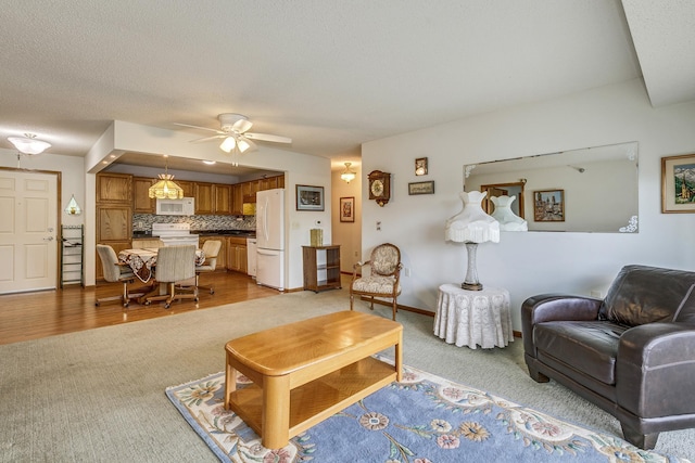 living area with light carpet, ceiling fan, and baseboards