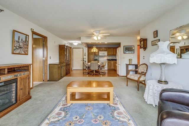 living area featuring ceiling fan, light colored carpet, a fireplace, and baseboards