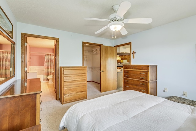 bedroom featuring a closet, light colored carpet, a spacious closet, ensuite bathroom, and ceiling fan
