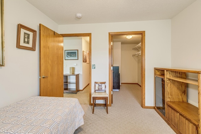 bedroom with a walk in closet and light carpet