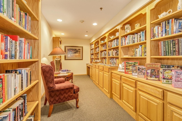 living area featuring light colored carpet, bookshelves, recessed lighting, and baseboards