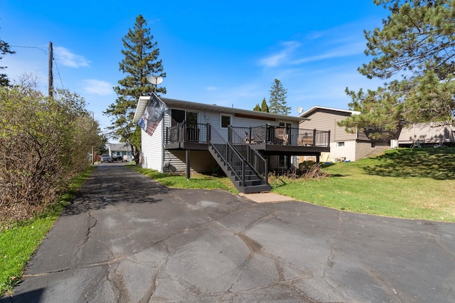 view of front of house featuring a wooden deck, a front lawn, stairs, and driveway