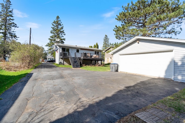 view of front facade with stairway, a wooden deck, a garage, and an outbuilding