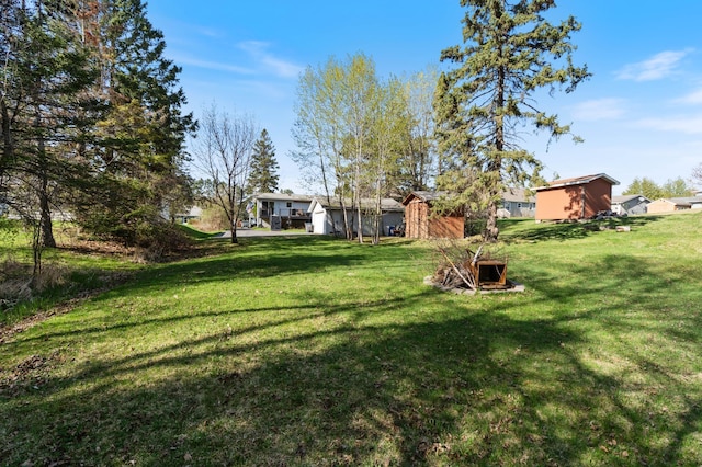 view of grassy yard featuring a storage shed and an outdoor structure