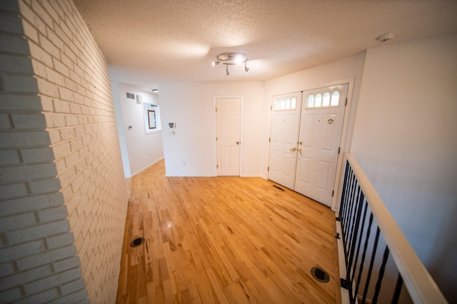 1723 Teton Ln NE, Rochester, MN 55906 - entrance foyer with light wood-style floors, a textured ceiling, brick wall, and baseboards