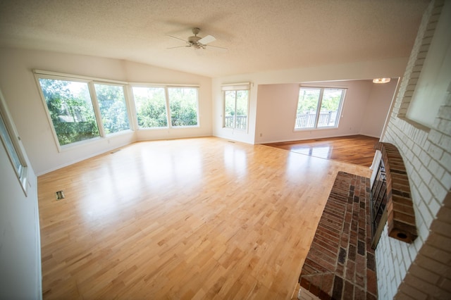 1723 Teton Ln NE, Rochester, MN 55906 - unfurnished living room featuring ceiling fan, a textured ceiling, wood finished floors, baseboards, and a brick fireplace