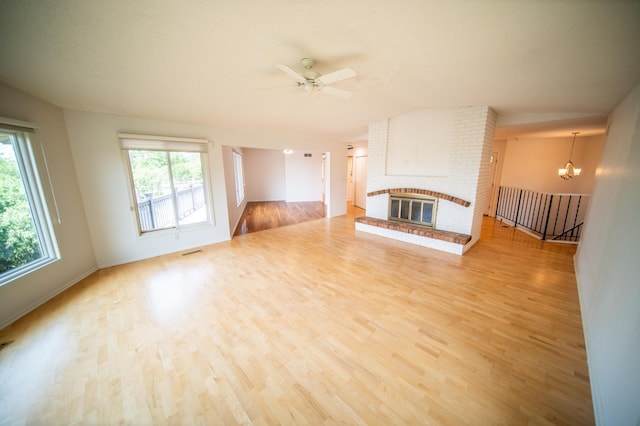1723 Teton Ln NE, Rochester, MN 55906 - unfurnished living room with a chandelier, light wood-style flooring, a brick fireplace, ceiling fan, and vaulted ceiling