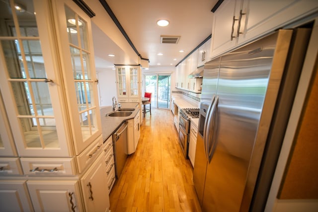 1723 Teton Ln NE, Rochester, MN 55906 - kitchen with appliances with stainless steel finishes, a sink, under cabinet range hood, light wood-style flooring, and glass insert cabinets