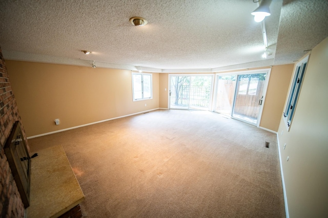1723 Teton Ln NE, Rochester, MN 55906 - carpeted spare room featuring a textured ceiling, baseboards, and a brick fireplace