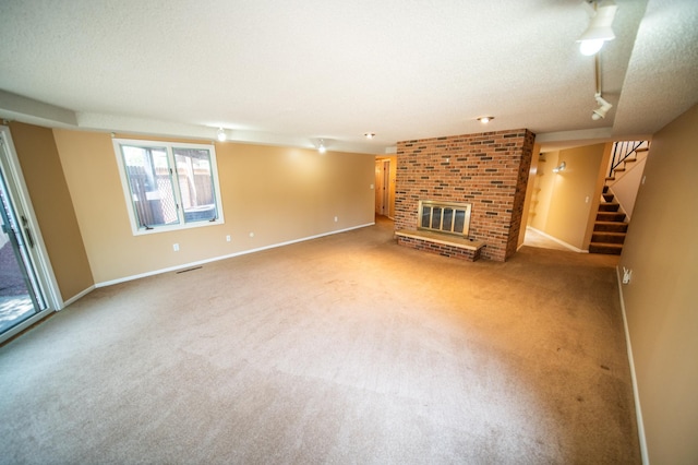 1723 Teton Ln NE, Rochester, MN 55906 - unfurnished living room with track lighting, carpet floors, a brick fireplace, stairway, and a textured ceiling